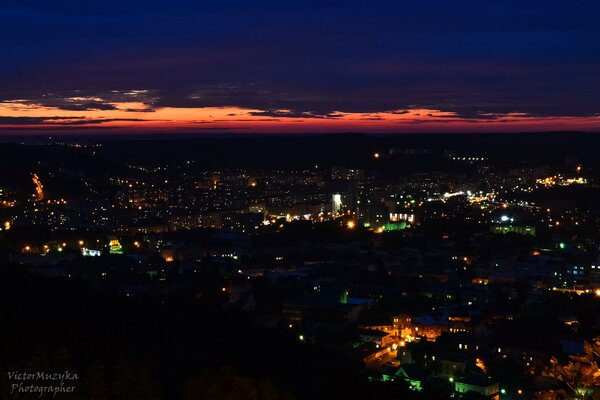 Zachód słońca nad nocnym miastem z pomarańczowymi chmurami