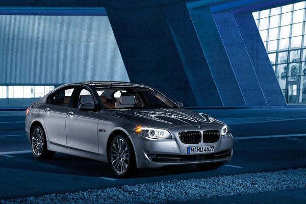 A grey BMW is standing in a huge room with large windows