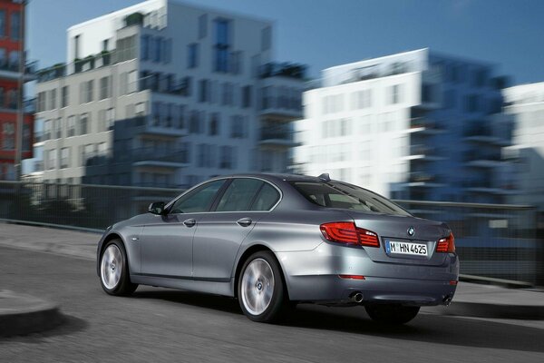 A grey BMW car is driving through the city