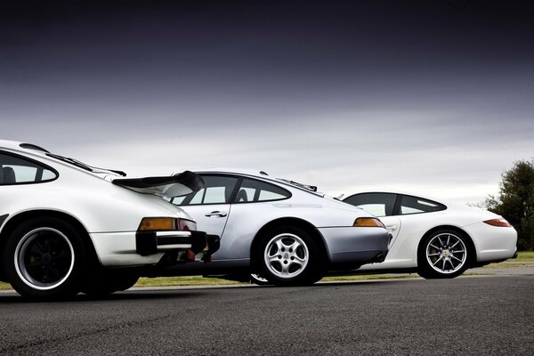 Three Porsche cars on the road. Rear bumper