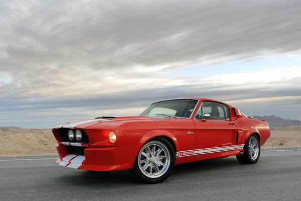 Red mustang on the road against the clouds