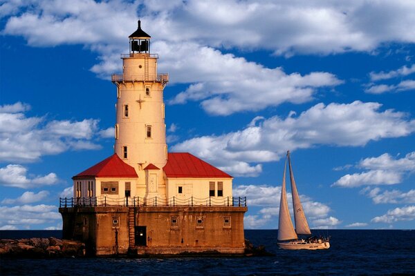 Lighthouse and yacht in the blue sea