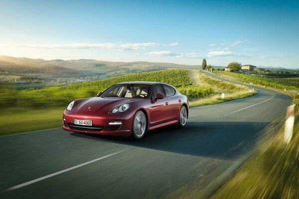 The red porsche is driving fast on the road