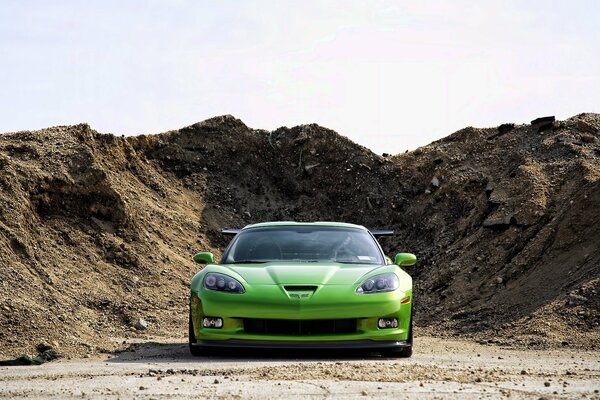 Green sports chevrolet on the background of an earthen embankment