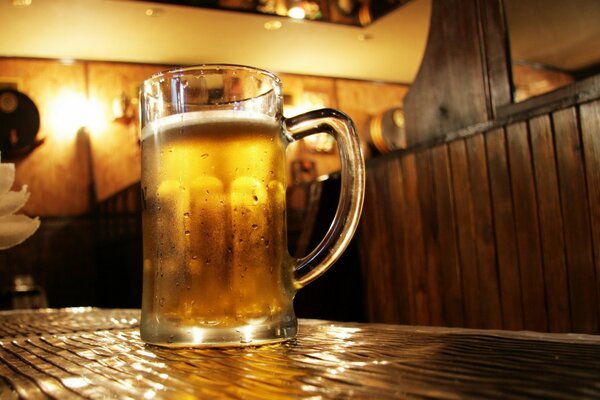 Ein großer Becher kaltes Bier auf einem Tisch in einer Bar