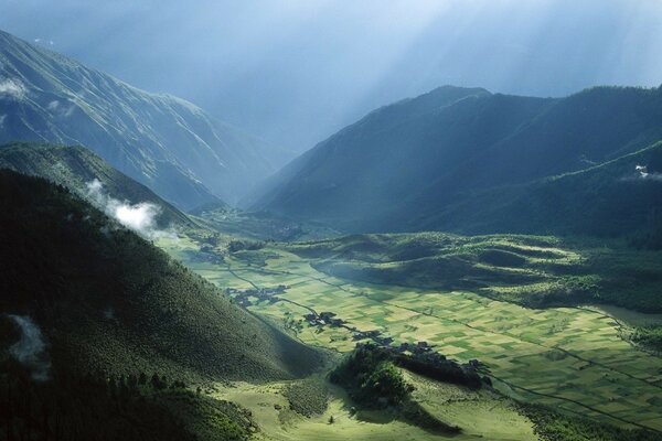The sun illuminates the field among the mountains