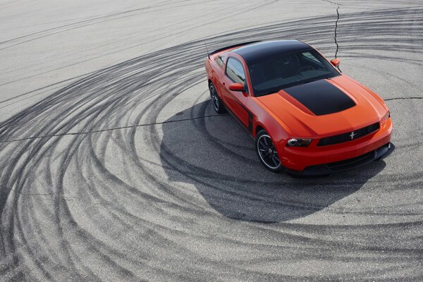 Orange car with a black roof in a skid