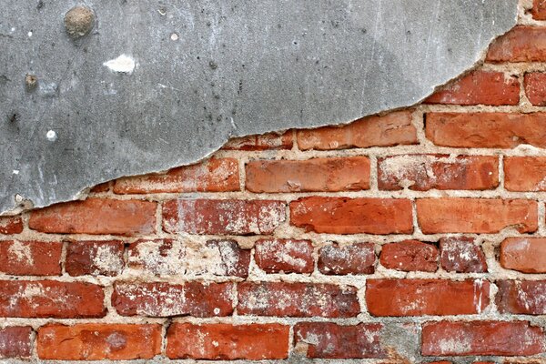 Die alte Mauer aus rotem Backstein ist halb mit Putz bedeckt