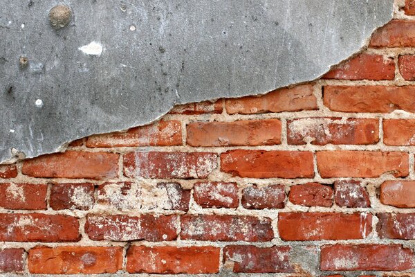 Старая стена из красного кирпича покрытая наполовину штукатуркой