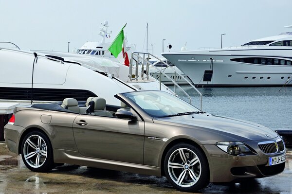 Convertibile BMW grigio su uno sfondo di yacht