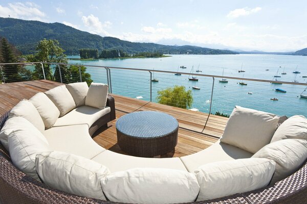 Полукруглый уютный диван на террасе с видом на озеро