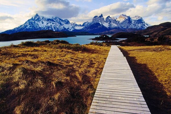 Sendero de madera hacia las montañas y el lago