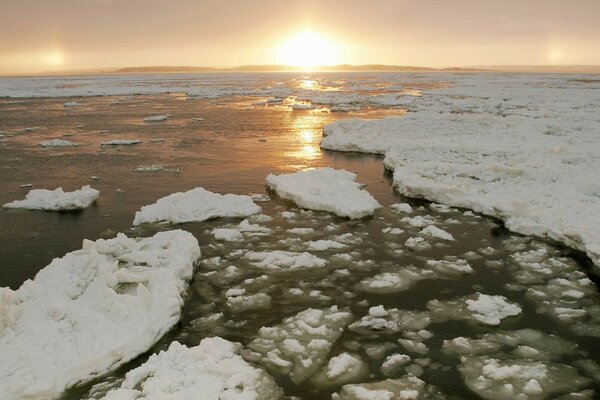 El río, el agua con hielo y el sol se va al atardecer