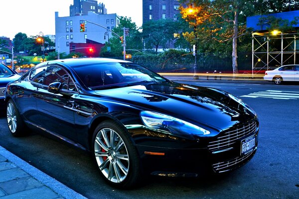 Aston martin negro brillante en la carretera de la ciudad