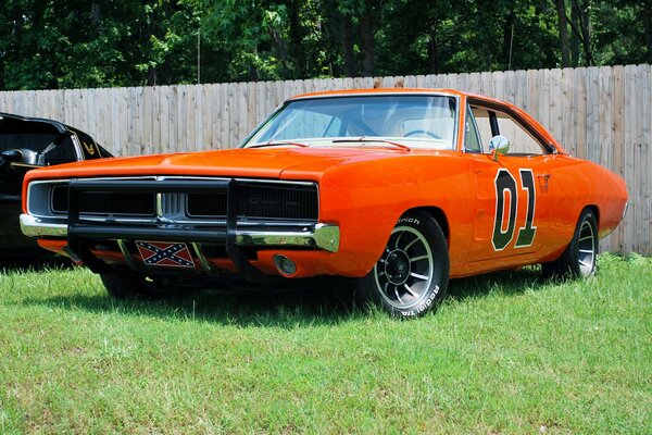 The orange car is standing in the sun