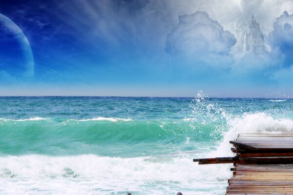 Las olas verdes del mar se estrellan contra el muelle bajo el cielo azul, en el que se ve el castillo de aire de las nubes