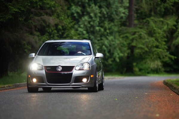 A car with a light is driving along a road in the forest