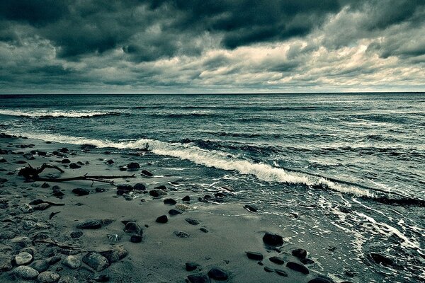 Sandstrand. Dunkler Himmel und blaues Meer