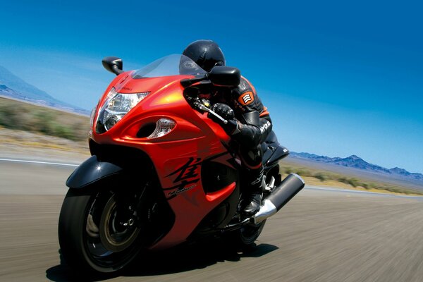 Red motorcycle rides at high speed on the road