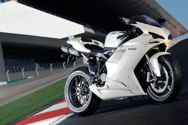 A white motorcycle bike stands against the background of the building