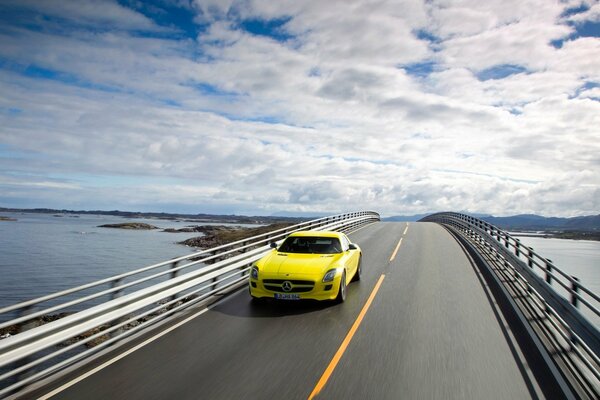 Eine Brücke mit Wolken. Gelber Mercedes