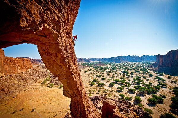 Un uomo si arrampica su una roccia in un canyon del deserto