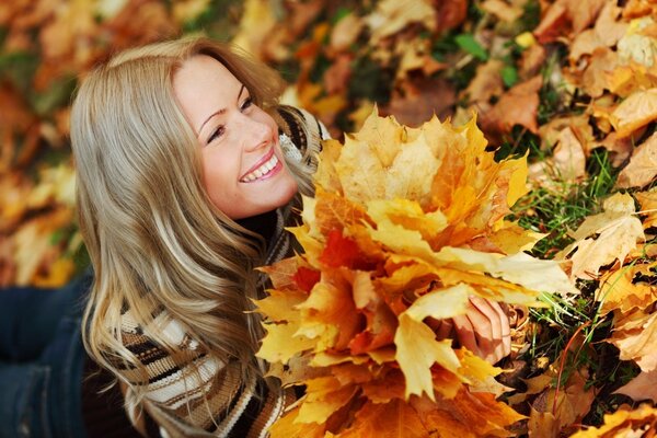 Ragazza sorridente con un mazzo di foglie cadute