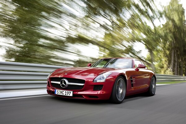 Red Mercedes is driving fast on the road