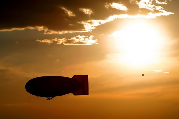 Airship and balloon in the sky at sunset