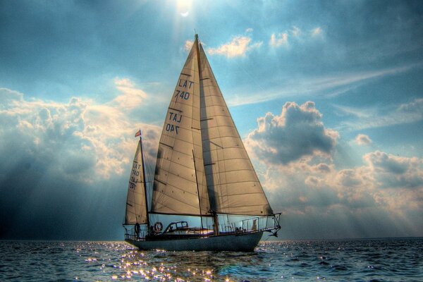 Barca a vela che galleggia su un mare mosso contro un cielo nuvoloso