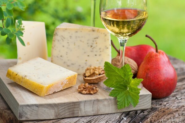 Slices of cheese on a board with white wine