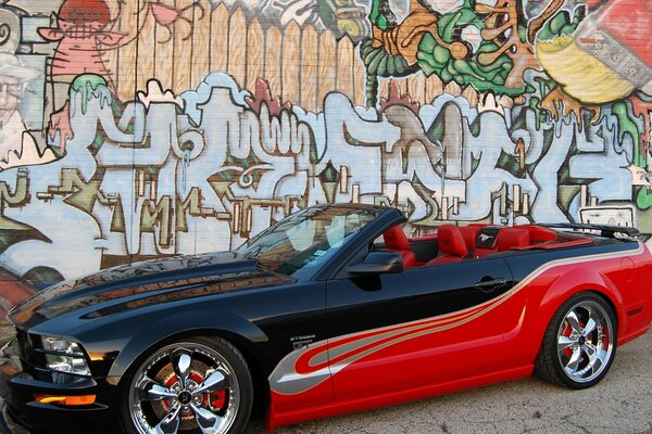 The red car is standing at the graffiti wall