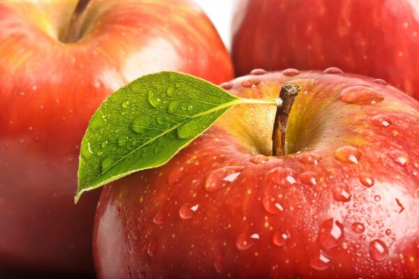 Wassertropfen auf einem roten Apfel mit einem Blatt