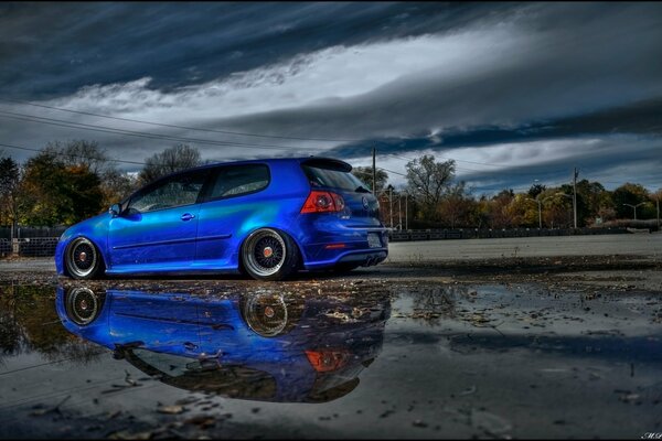 Volkswagen Golf car blue on a wet road background