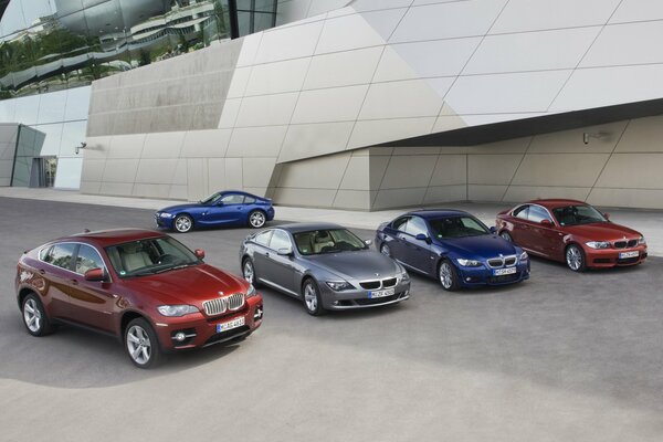 En el estacionamiento hay cinco BMW multicolores. En primer plano, cuatro, y uno más en el fondo