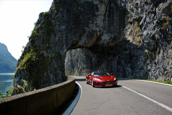 Coche rojo en la carretera pasa el arco