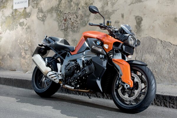 A black bike with a colored body element stands at the concrete wall and curb