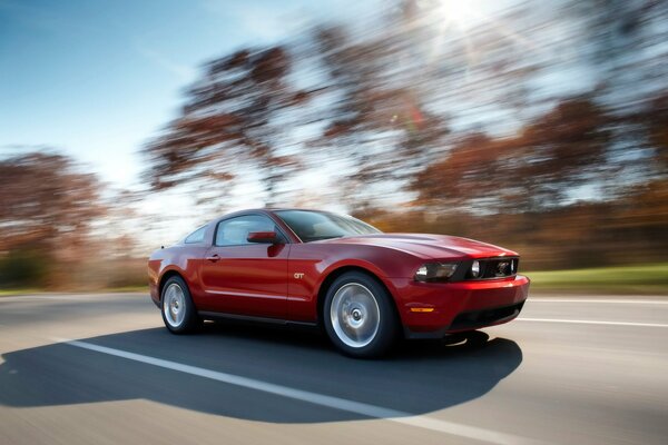 Una Ford Mustang rossa corre lungo la strada