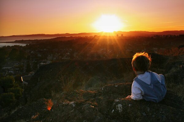 Niño por la mañana en medio de la puesta de sol rojo