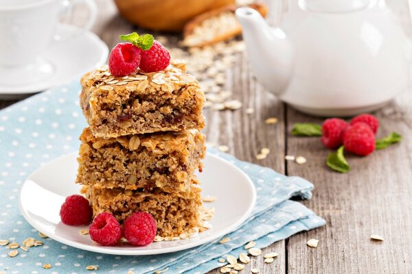 Three pieces of cake on a white plate, decorated with raspberries