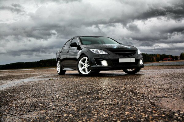 Mazda 6 auf dem Asphalt vor dem Hintergrund der Wolken