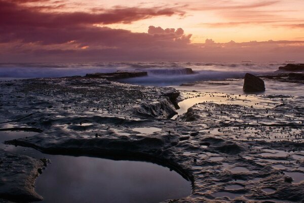 Olas extraordinarias en la noche contra nubes y piedras