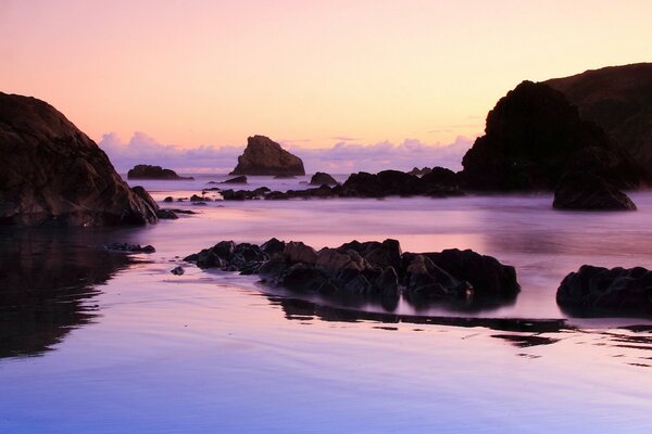 Sunset on a background of purple water and rocks