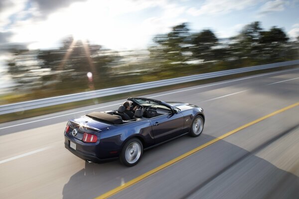 A dark convertible is driving at high speed