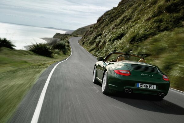 Ein dunkelgrüner Porsche miaut mit hoher Geschwindigkeit auf der Straße