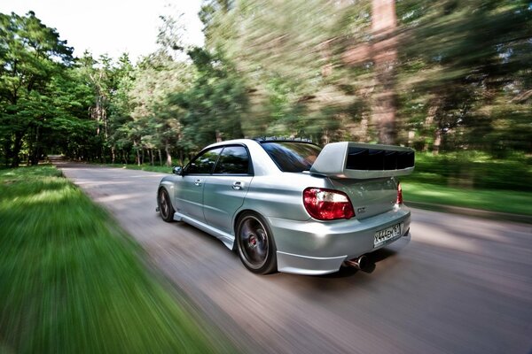 Blurred background of a country road with a subaru car