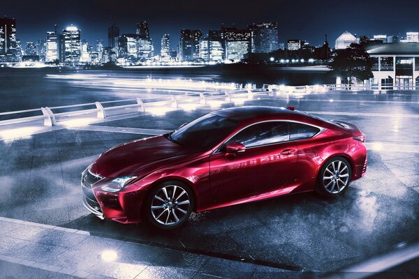 Roter Lexus rc 350 bei Nacht vor dem Hintergrund einer Metropole