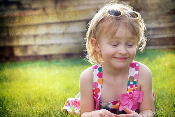 A cheerful girl is lying on the green grass