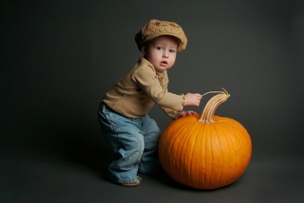 Bebé con calabaza sobre fondo gris