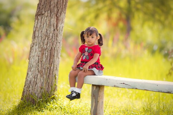 Niña sentada en un banco en verano